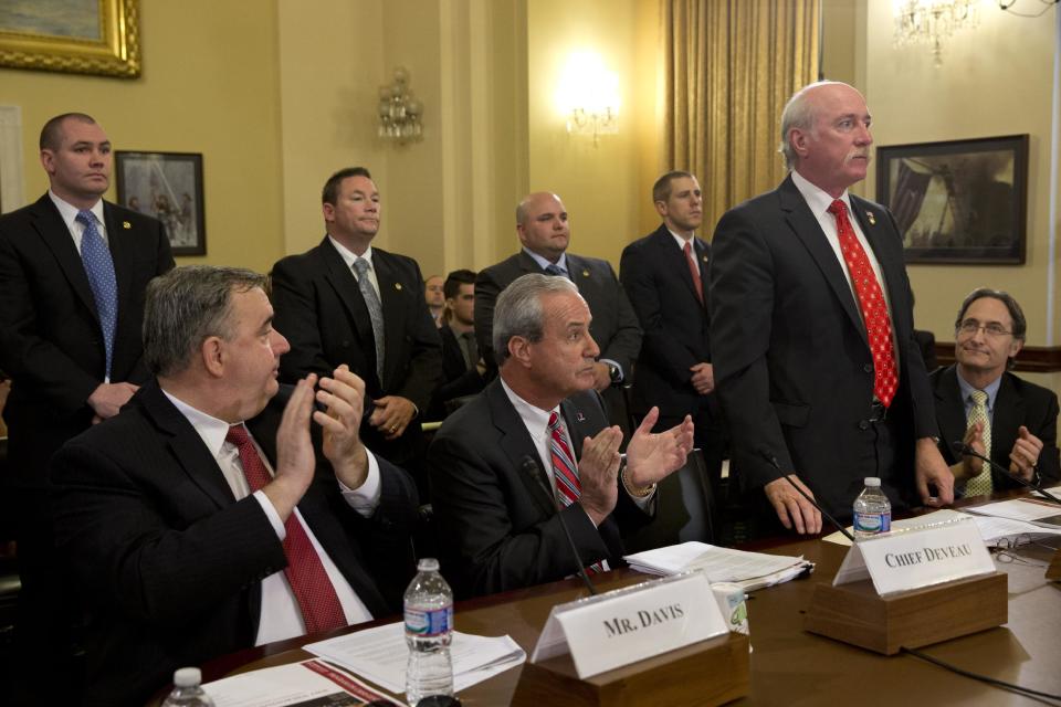 Boston Police Department Commissioner, and Fellow at Harvard University, Edward Davis, left, and Watertown, Mass. Police Chief Edward Deveau, center, applaud as Watertown Police Sgt. Jeffrey Pugliese, and fellow police officers from Watertown as they stand to be acknowledged on Capitol Hill in Washington, Wednesday, April 9, 2014, during the House Homeland Security Committee hearing about the Boston Marathon Bombings leading up to the year anniversary of the attack. At right is Harvard University Professor Herman “Dutch” Leonard. (AP Photo/Jacquelyn Martin)