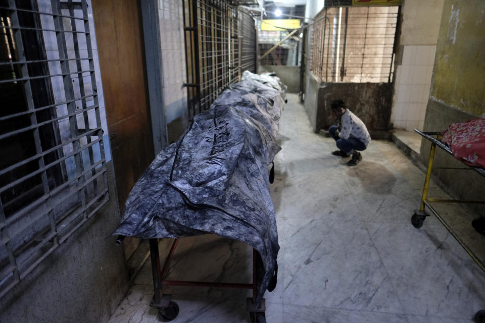 A man sits near bodies of people killed in a train fire in Dhaka, Bangladesh, Tuesday, Dec. 19, 2023. Bangladesh’s railway minister blamed it on the country’s main opposition Bangladesh Nationalist Party, led by former Prime Minister Khaleda Zia, accusing it of “arson” and “sabotage” to thwart the national election slated for Jan. 7. Zia's party, which is boycotting the election, issued a statement denying the accusation. (AP Photo/Mahmud Hossain Opu)