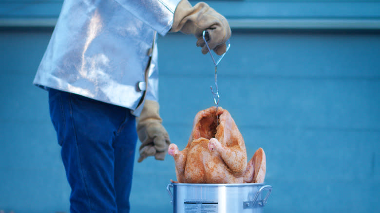 Person dipping turkey into deep fryer