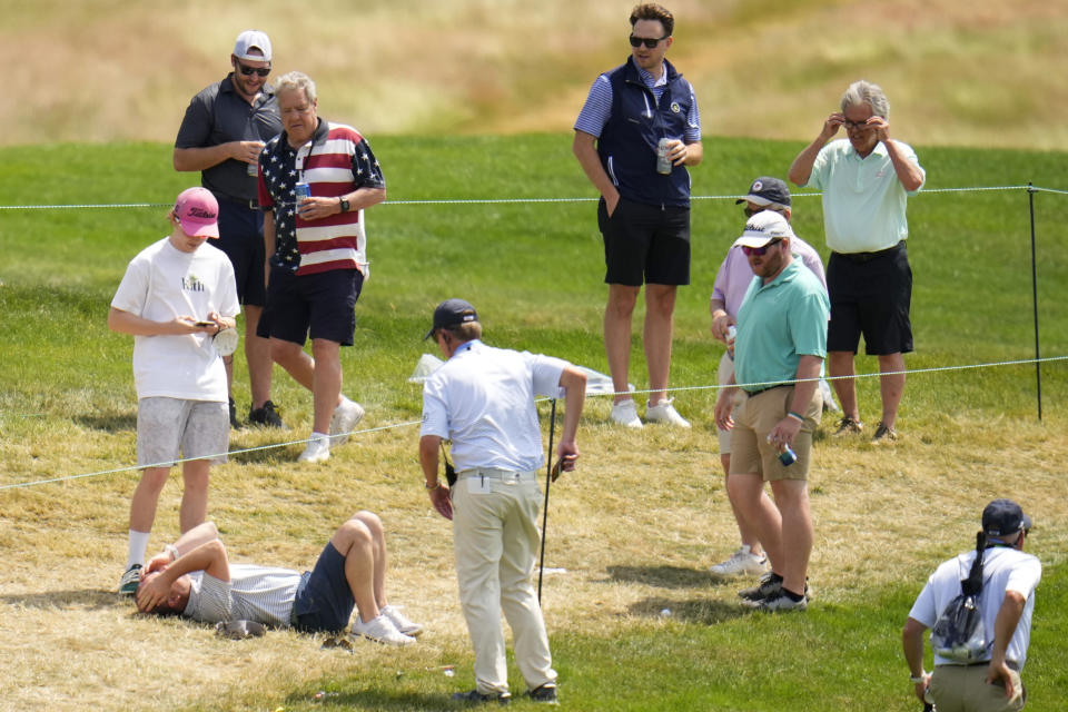 CORRECTS TO SAM HORSFIELD‬, OF ENGLAND, NOT PHIL MICKELSON - A fan, bottom left, reacts after being hit by a ball from Sam Horsfield‬, of England, on the third hole during the second round of the U.S. Open golf tournament at The Country Club, Friday, June 17, 2022, in Brookline, Mass. (AP Photo/Julio Cortez)