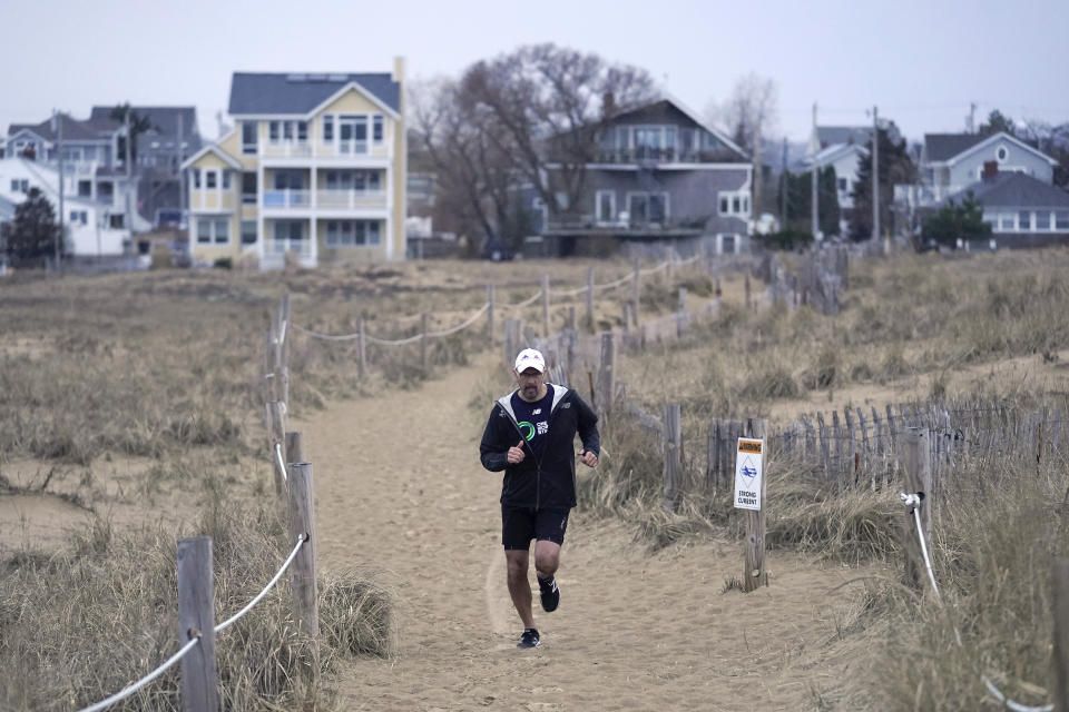Dave Fortier, president of One World Strong Foundation, trains for the 2023 Boston Marathon as he runs along a path to a beach, Tuesday, April 4, 2023, in Newburyport, Mass. Fortier was hit in the foot by shrapnel in the 2013 bombing and doesn't remember finishing the race. (AP Photo/Steven Senne)