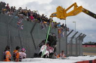 Track workers remove the car of Alfa Romeo driver Guanyu Zhou of China after a crash at the start of the British Formula One Grand Prix at the Silverstone circuit, in Silverstone, England, Sunday, July 3, 2022. (AP Photo/Frank Augstein)