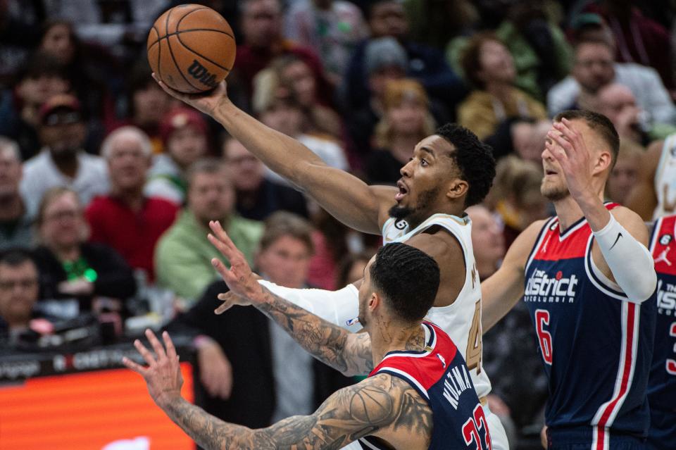Cleveland Cavaliers' Donovan Mitchell drives between Washington Wizards' Kristaps Porzingis (6) and Kyle Kuzma (33) during the second half of an NBA basketball game in Cleveland, Friday, March 17, 2023. (AP Photo/Phil Long)