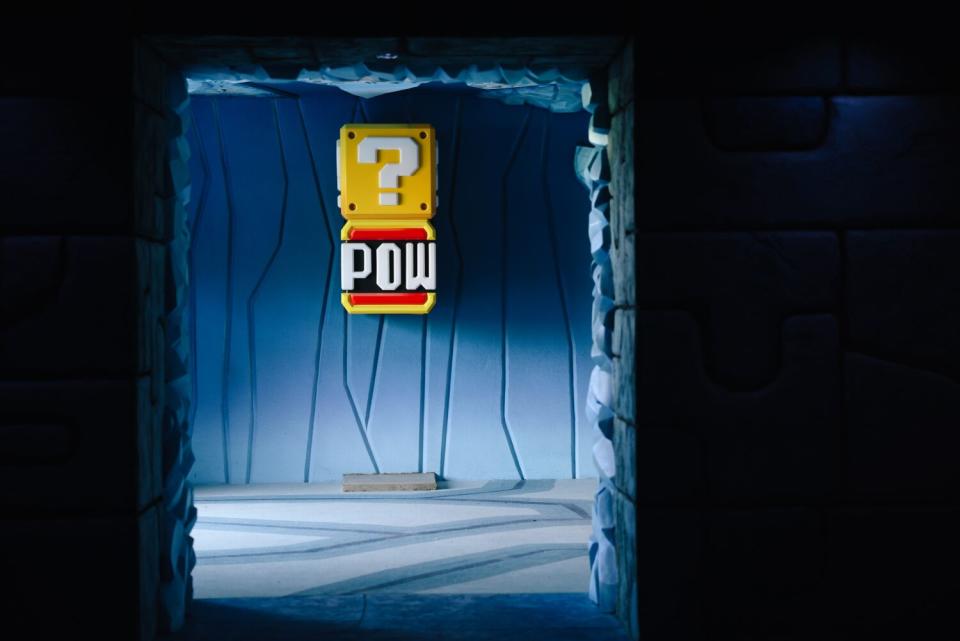 A wall opening reveals a sign containing the word &quot;pow&quot; and a question mark.