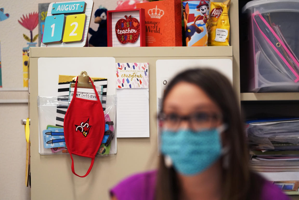 FILE - Wearing a mask to protect against the spread of COVID-19, kindergarten teacher Amber Ximenz prepares her classroom at Southside Independent School District in San Antonio, on Aug. 13, 2020. Texas Gov. Greg Abbott’s executive order that forbids school districts from imposing mask mandates on schools to prevent the spread of COVID-19 was upheld Monday, July 25, 2022, by a divided federal appeals court panel in New Orleans. (AP Photo/Eric Gay, File)