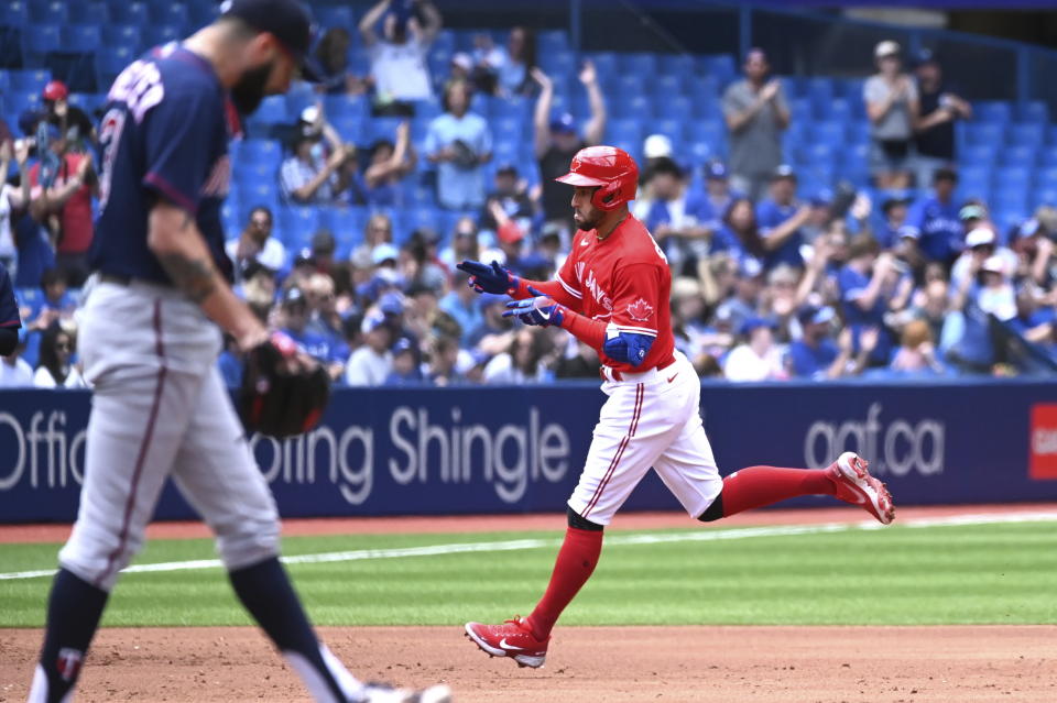 Toronto Blue Jays' George Springer, right, rounds the bases after hitting a solo home run off Minnesota Twins starting pitcher Devin Smeltzer, left, in the first inning of a baseball game in Toronto, Sunday, June 5, 2022. (Jon Blacker/The Canadian Press via AP)