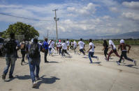 Haitians deported from the United States run back to the tarmac to try to get on the same plane they were deported in, in an attempt to return to the United States, at the Toussaint Louverture airport in Port-au-Prince, Haiti Tuesday, Sept. 21, 2021 (AP Photo/Joseph Odelyn)