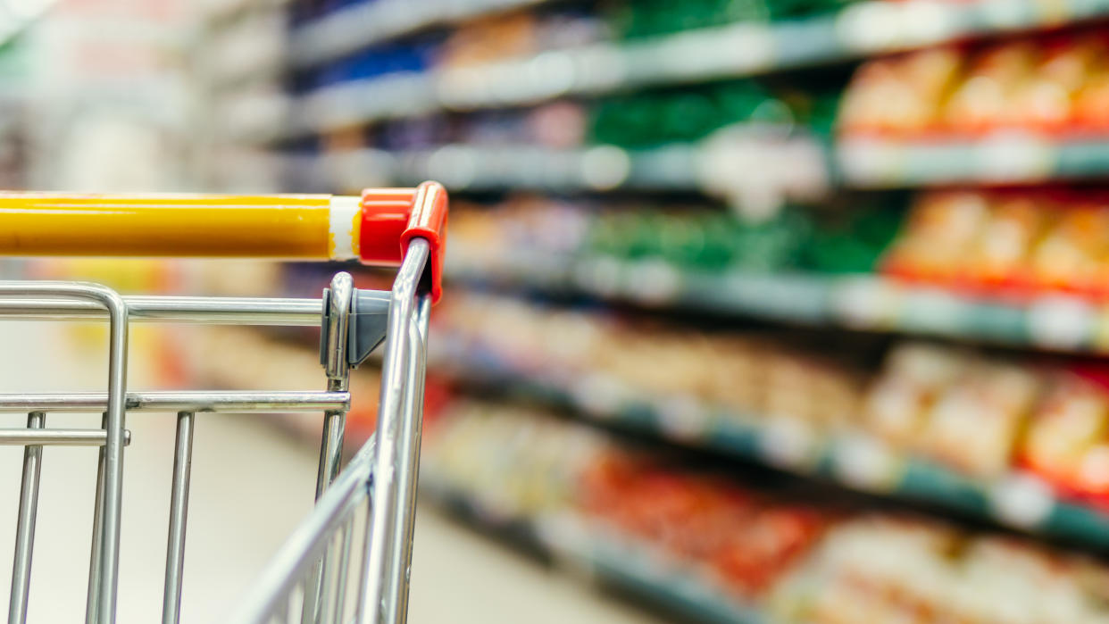 Shopping cart in supermarket. Part of shopping trolley in supermarket aisle. Blurred shelves in grocery store and trolley. Copy space for text or design.