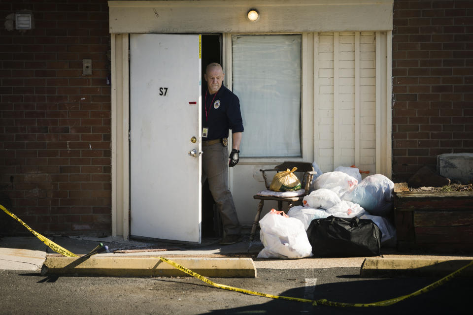 FILE - In this Feb. 26, 2019 file photo, an investigator steps out from the Robert Morris Apartments in Morrisville, Pa. Shana Decree and her daughter Dominique Decree who are charged in the killing of their close family members are expected to enter pleas Tuesday, Feb. 18, 2020 in court in Doylestown, Pa. (AP Photo/Matt Rourke, File)