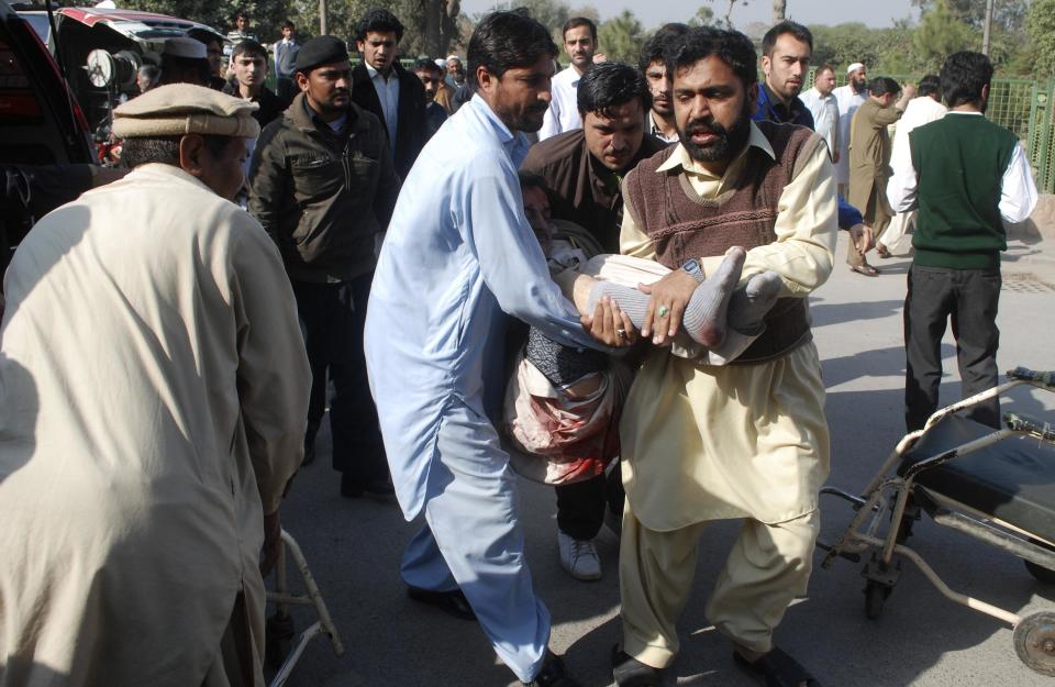 Men carry a victim, who was wounded in an explosion in a Shi'ite mosque, outside a hospital in Peshawar