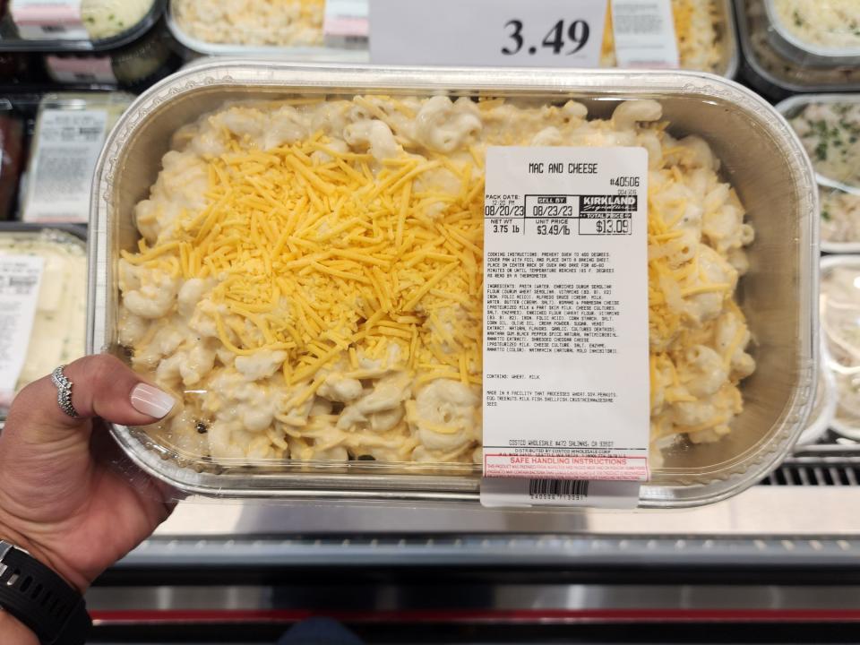 The writer holds a container of mac and cheese at Costco