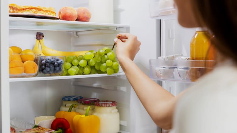 woman removing grapes from refrigerator