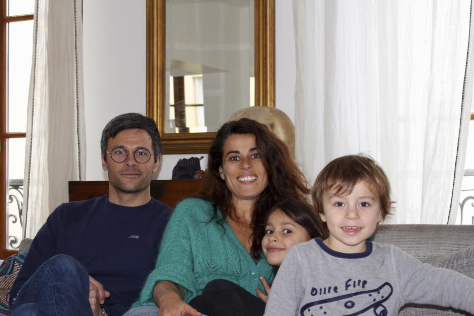 In this photo taken Thursday April 30, 2020 Mathilde Manaud et Kimkhi Nguyen, left, pose on a sofa with their children Mila, 7, and Andre, 3, in Paris. As France prepares to start letting public life resume after eight weeks, many parents are deeply torn over a question without a clear or conclusive answer: Should I send my child back to school? The French government is easing some of the closure and home-confinement orders it imposed March 17 to curb coronavirus infections, with businesses permitted to reopen, residents cleared to return to workplaces and schools welcoming some students again starting Monday. (AP Photo/Oleg Cetinic)