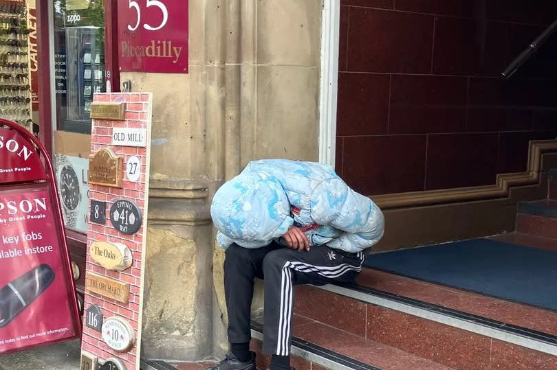 A man is slumped motionless on the steps of a hotel on Piccadilly -Credit:Manchester Evening News