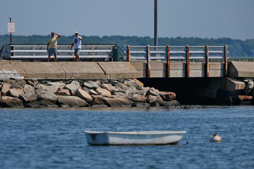 Two men look out into Buzzards Bay as they walk across the West Island causeway and bridge on Goulart Memorial Drive in Fairhaven.