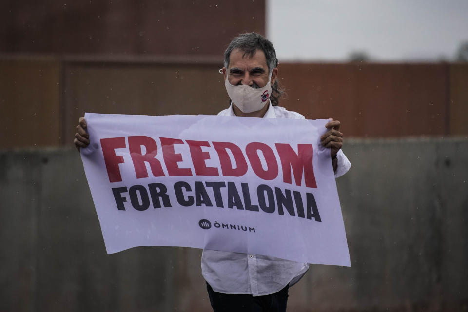 Jordi Cuixart, one of the Catalan leaders imprisoned for their role in the 2017 push for an independent Catalan republic, holds a banner at Lledoners prison in Sant Joan de Vilatorrada, near Barcelona, Spain, Wednesday, June 23, 2021. Nine separatists pardoned by the Spanish government are expected to leave the prisons where they were serving lengthy terms for organizing a bid for an independent northeastern Catalonia region nearly four years ago. Spain's official gazette published earlier in the day the government decree pardoning them. (AP Photo/Joan Mateu)