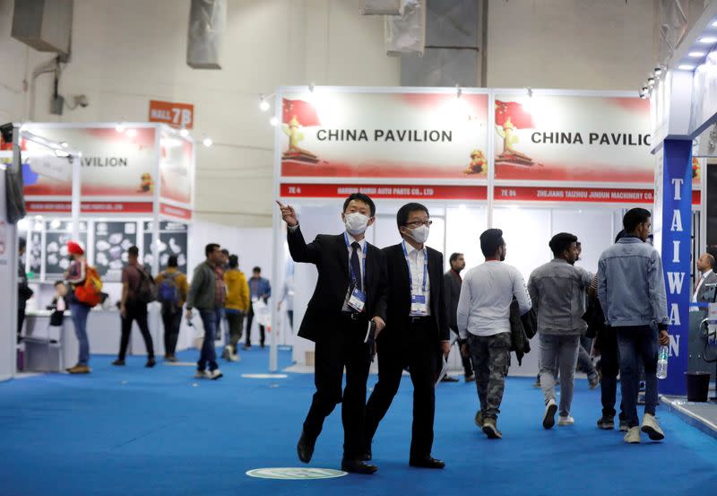 FILE PHOTO: People wearing mask are seen near the stalls inside the China pavilion at the India Auto Expo 2020 - Components in New Delhi