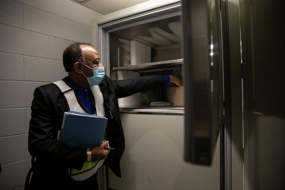 City of Brockton Executive Health Officer Eno Mondesir shows the media the temperature-monitored refrigerator where the Moderna COVID-19 vaccine is stored during the vaccination clinic for Brockton's first responders at Brockton High School on Monday, Jan. 11, 2021.