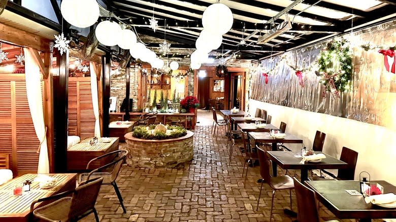 enclosed outdoor patio with cobblestone floor and dining tables