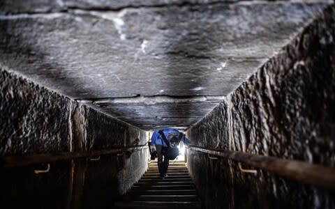 A man walks through a passage in the well-known bent pyramid of King Sneferu in Dahshur, 20 miles south of Cairo, which had been closed to visitors since 1965 and has now re-opened - Credit: Mohamed El-Shahed/AFP
