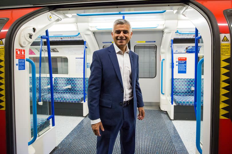 London Mayor Sadiq Khan poses in front of the open doors of a Tube train car