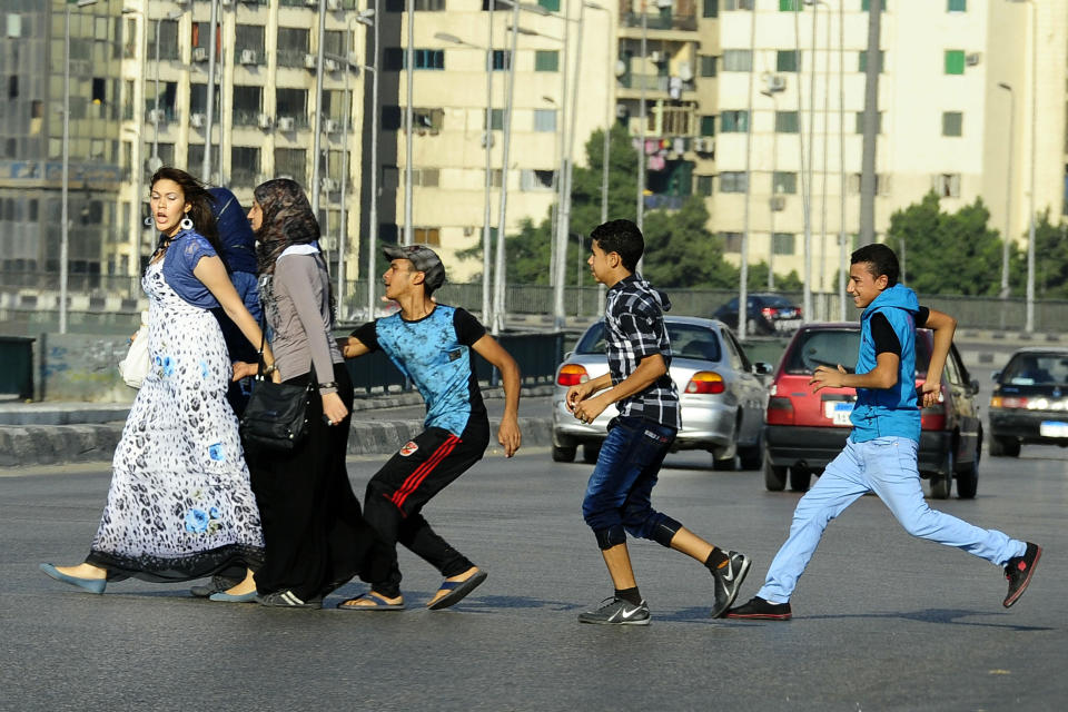 FILE - In this Aug. 20, 2012 file photo, an Egyptian youth, trailed by his friends, gropes a woman crossing the street with her friends in Cairo, Egypt. A video posted on Facebook Aug. 15, 2018, by an Egyptian woman who says a man stalked her at a bus stop has stirred online debate, with many -- including women -- taking the man’s side. Some say he was politely flirting and the woman overreacted, while others have speculated about what she was wearing, suggesting she was the one at fault. The diverging responses point to the difficulty in combatting the rampant sexual harassment on Egypt’s streets. (AP Photo/Ahmed Abd El Latif, El Shorouk Newspaper, File)