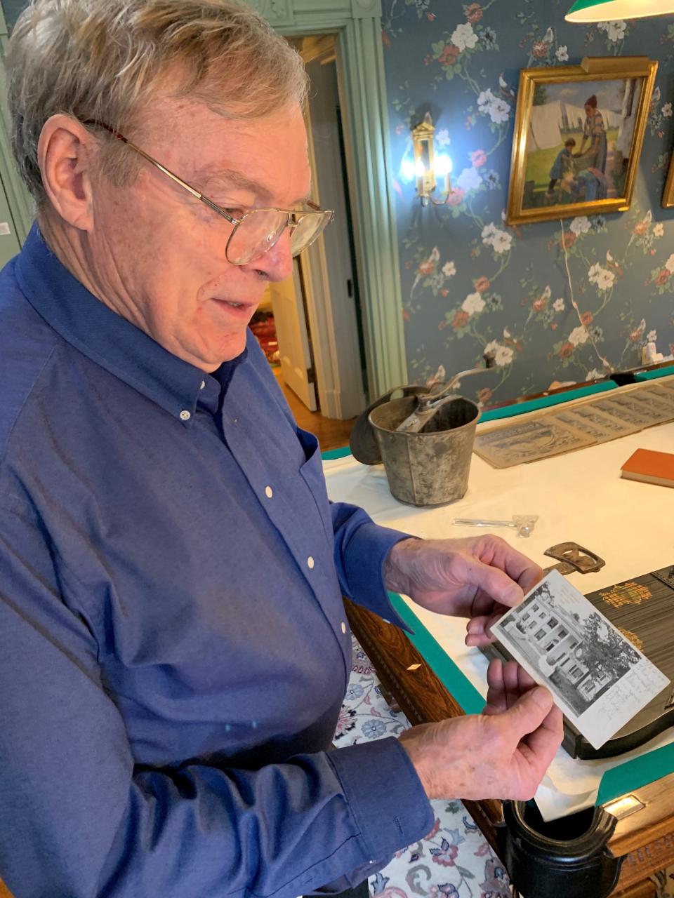 In this 2019 file photo, Bob Haan holds a postcard from the 1904 St. Louis World’s Fair depicting the Connecticut state pavilion, which was disassembled after the fair and moved to Lafayette. The building now stands at 920 E. State Street and houses the Haan Mansion Museum of Indiana Art.