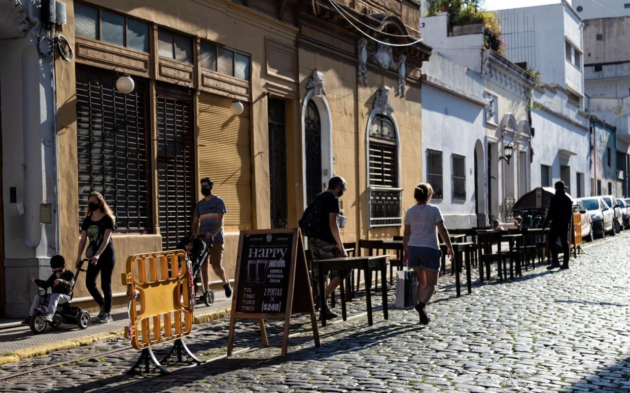 A few people walk past a deserted bar with outdoor seating in on a cobbled street - Anita Pouchard Serra/Bloomberg