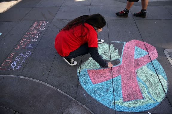 A woman draws a red AIDS ribbon on Castro Street in San Francisco for World AIDS Day, Dec. 1, 2015.