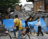 <p>People pause to look at a collapsed house following an earthquake in Ibaraki City, north of Osaka prefecture on June 18, 2018. (Photo: STR/AFP/Getty Images) </p>