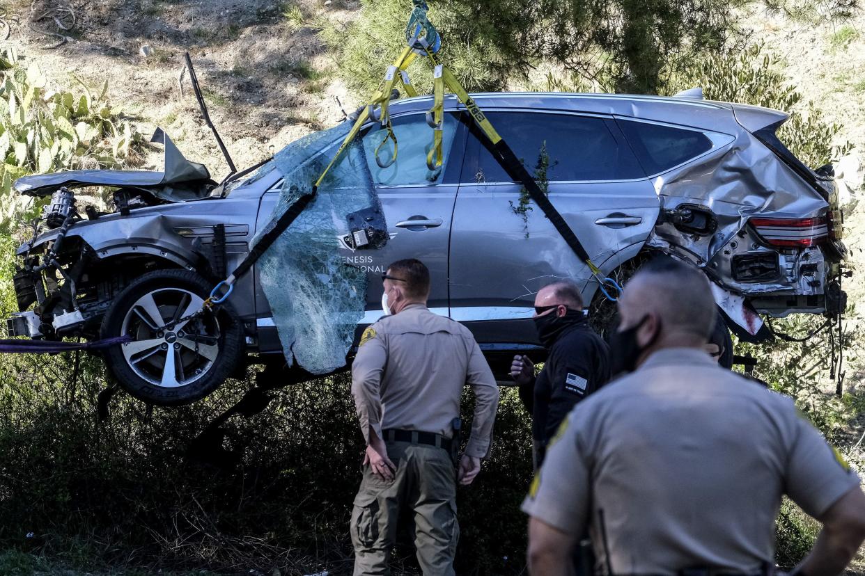 A crane lifts Tiger Woods' destroyed vehicle from a Los Angeles County park.