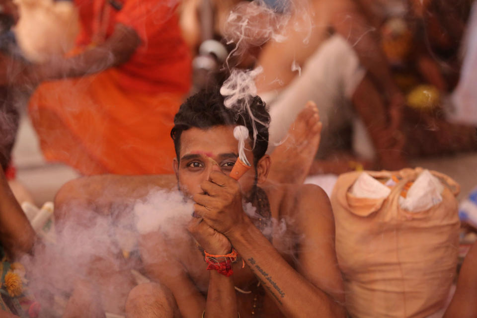 A Hindu holy man smokes as he waits to register for the annual pilgrimage to the Amarnath cave shrine in Jammu, India, Monday, July 1, 2019. Thousands of Hindu pilgrims began the arduous trek to an icy Himalayan cave in disputed Kashmir on Monday, with tens of thousands of Indian government forces guarding roads and mountain passes. (AP Photo/Channi Anand)