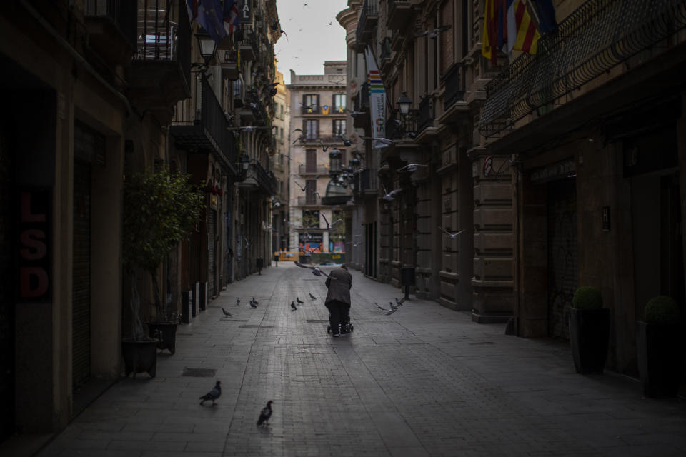 A woman pushes a cart with her belongings as she walks along an empty street in downtown Barcelona, Spain, March 21, 2020. The image was part of a series by Associated Press photographer Emilio Morenatti that won the 2021 Pulitzer Prize for feature photography. (AP Photo/Emilio Morenatti)