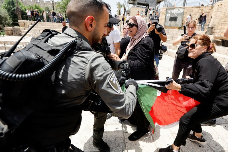 Foto del domingo de un agente de seguridad junto a una manifestante con una bandera palestina cerca de la entrada a la Ciudad Vieja de Jerusalén