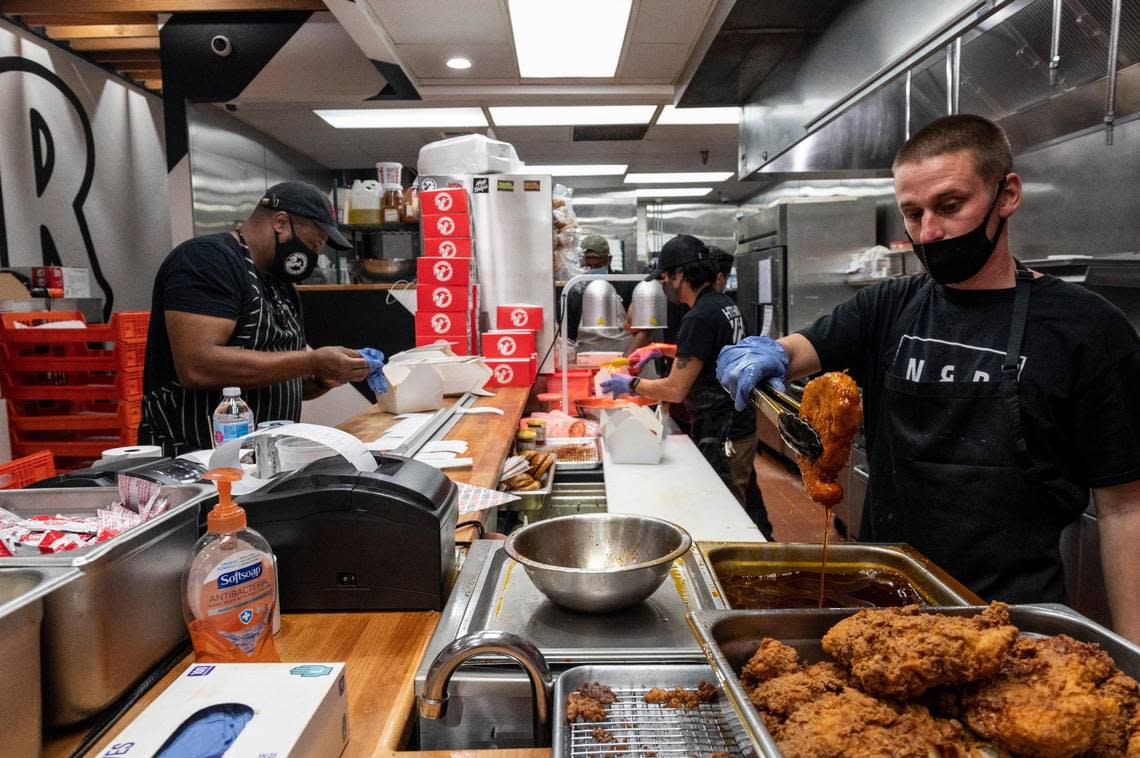 Owner Cecil Rhodes, left, works on orders while Matt Rocha, right, lifts a chicken thigh out of hot oil and Gavin Okamoto, center, makes sandwiches at Nash and Proper’s new takeout restaurant on K Street in downtown Sacramento on Thursday, Sept. 24, 2020. Alie Skowronski/askowronski@sacbee.com