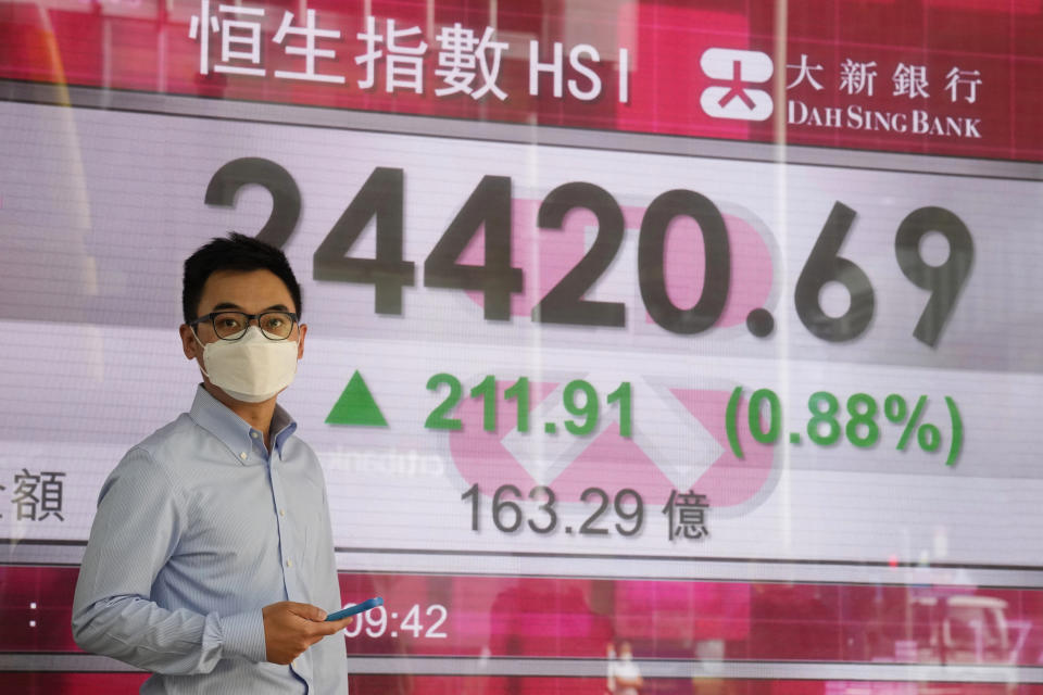 A man wearing a face mask walks past a bank's electronic board showing the Hong Kong share index in Hong Kong, Tuesday, Sept. 28, 2021. Asian shares mostly fell Tuesday as concerns about China chipped away at investor optimism following a mixed finish on Wall Street. (AP Photo/Kin Cheung)