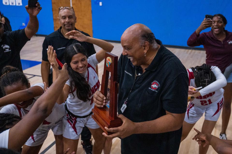 Palm Beach Central head coach Bruce Gaffney celebrates while holding the district championship trophy after the end of the District 8-7A girls basketball championship game between host Wellington and Palm Beach Central on Friday, February 3, 2023, in Wellington, FL. Final score, Palm Beach Central, 51, Wellington, 41.