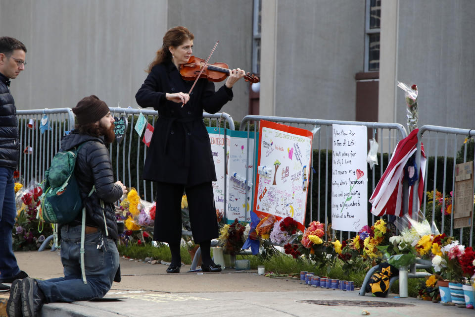 FILE - In this Sunday, Oct. 27, 2019 file photo, Monique Mead plays her violin on the sidewalk outside the Tree of Life synagogue in Pittsburgh on the first anniversary of the shooting at the synagogue, that killed 11 worshippers. (AP Photo/Gene J. Puskar)