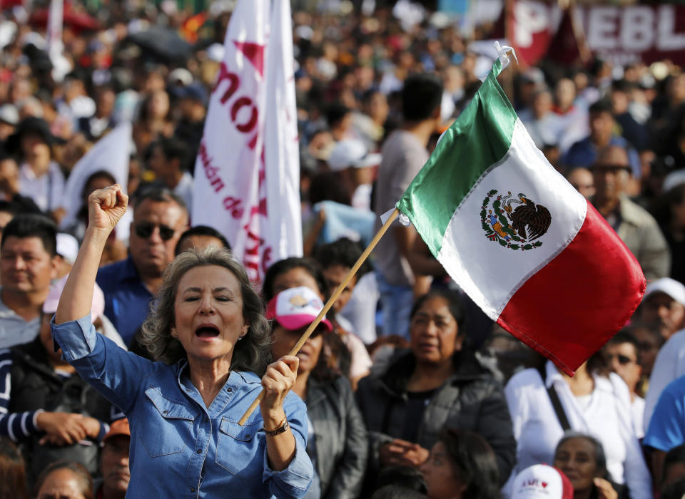 A supporters of Mexico's President Andres Manuel Lopez Obrador waves a Mexican flag during a rally to celebrate the one-year anniversary of his election, in Mexico City's main square, the Zocalo, Monday, July 1, 2019.(AP Photo/Fernando Llano)