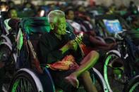 A tricycle driver smokes while attending an outdoor movie screening held by a private organization in Phnom Penh