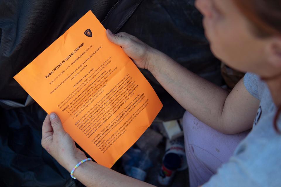 Ashley Hanson, 29, reads a Grants Pass police notice notifying her that she needs to move her camp. Right now, the unhoused are required to move every three days. “If they gave us a spot to be, I’d be there,” said Hanson.