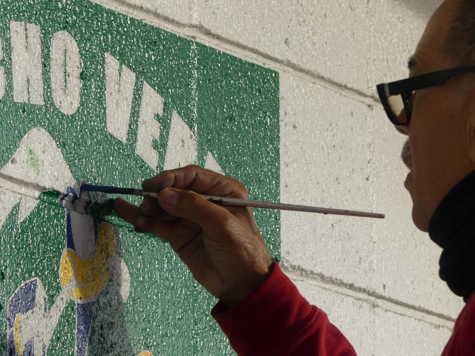 Business owner Miguel Gonzalez continues painting by hand, the Rancho Verde Elementary School logo, one of over a dozen for schools in the Apple Valley Unified School District.