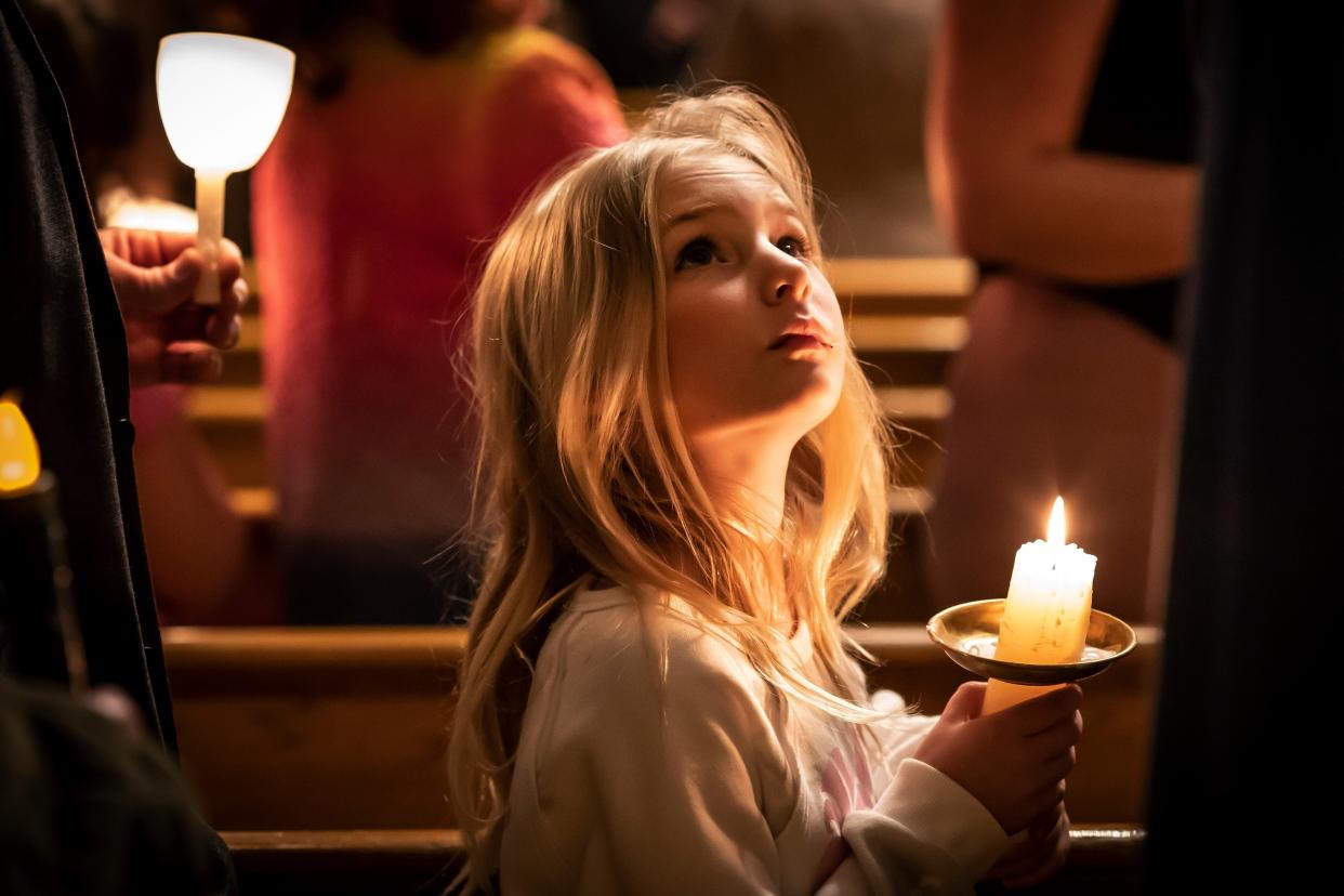 A girl looks at her mother while holding a candle during Good Friday service at St. Mary's Ukrainian Orthodox Cathedral in Allentown, Pa. 