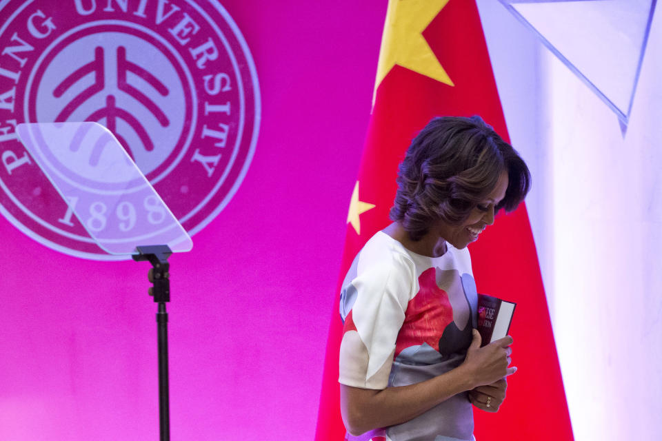 U.S. first lady Michelle Obama holds a book given to her as a gift from Peking University as she leaves a podium after her speech at Stanford Center in the Peking University in Beijing, China, Saturday, March 22, 2014. (AP Photo/Alexander F. Yuan)