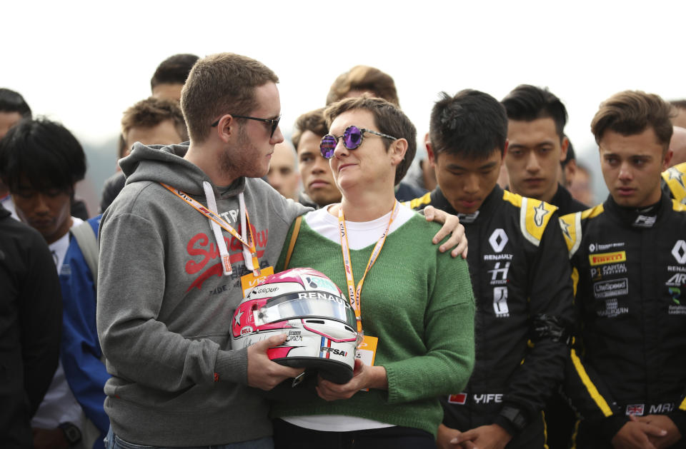 The mother and brother of Anthoine Hubert hold the helmet of Anthoine Hubert during a moment of silence at the Belgian Formula One Grand Prix circuit in Spa-Francorchamps, Belgium, Sunday, Sept. 1, 2019. The 22-year-old Hubert died following an estimated 160 mph (257 kph) collision on Lap 2 at the high-speed Spa-Francorchamps track, which earlier Saturday saw qualifying for Sunday's Formula One race. (AP Photo/Francisco Seco)