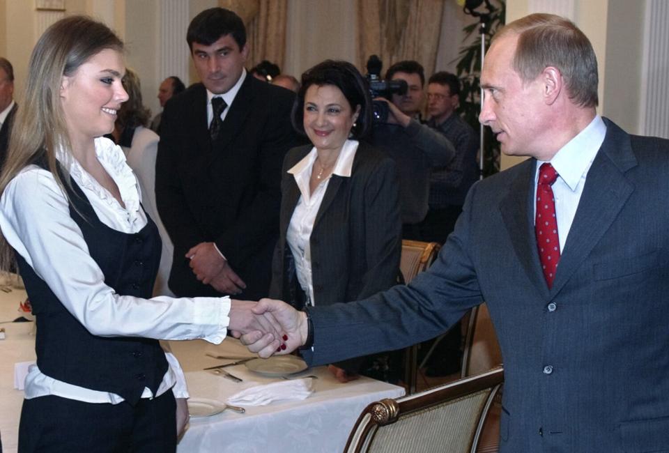 Russian President Vladimir Putin (R) shakes hands with famous Russian gymnasts Alina Kabayeva (C) and Svetlana Khorkina (L) during the meeting with sportsmen, candidates to Russian Olympic team for Olympics 2004, in the presidential residence in Novo-Ogaryovo outside Moscow, 10 March 2004. Vladimir Putin said Russian business is ready to support Russian sportsmen. AFP PHOTO / POOL (Photo credit should read SERGEI CHIRIKOV/AFP via Getty Images)