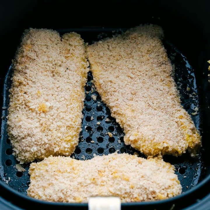 Three pieces of breaded cod in an air frying basket.