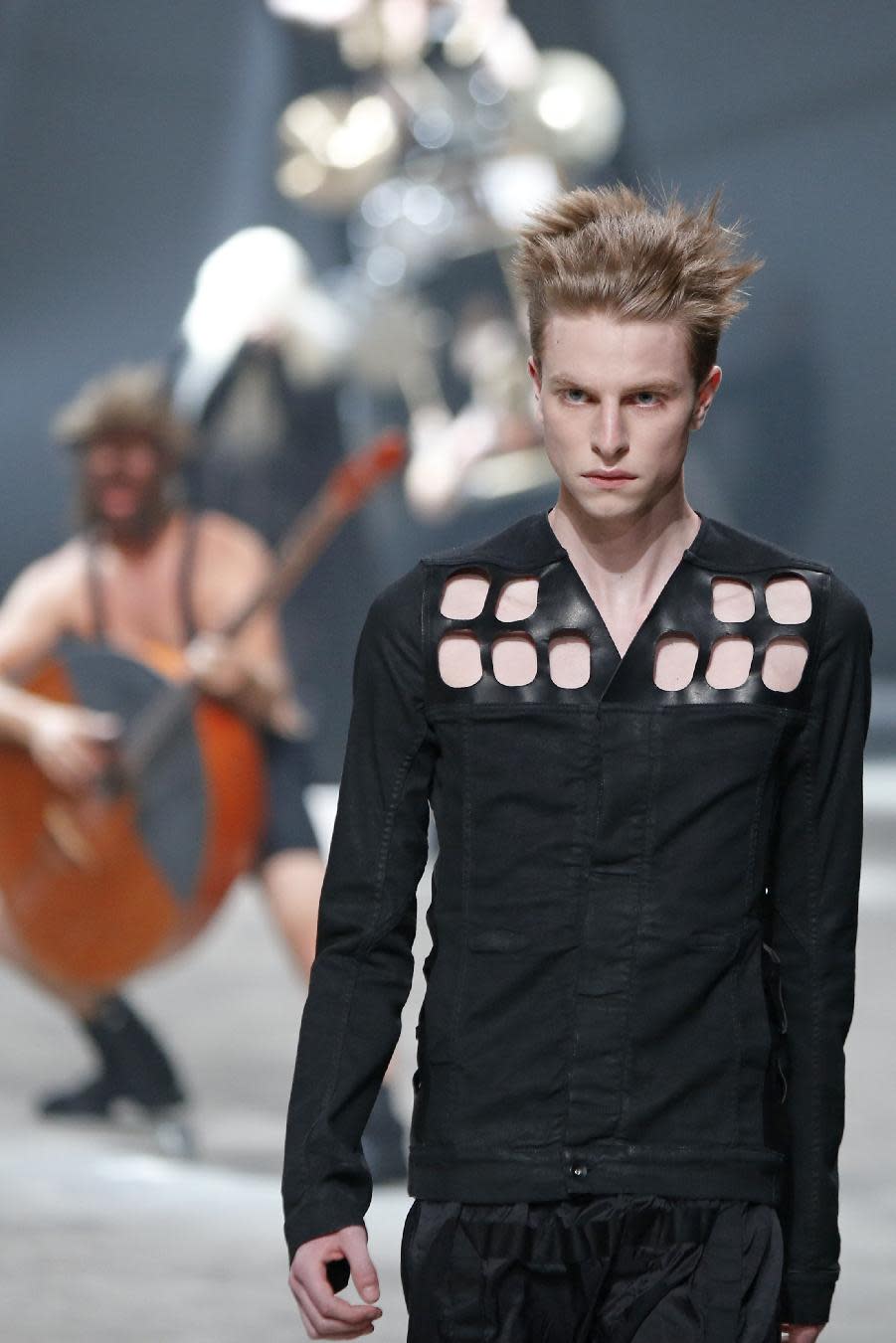 A model wears a creation by fashion designer Rick Owens as part of his men's fashion Spring-Summer 2014 collection, presented Thursday, June 27, 2013 in Paris, as Estonian metal/punk band Winny Puhh perform live, rear left. (AP Photo/Francois Mori)