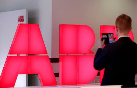 FILE PHOTO: A man takes pictures of the logo of Swiss power technology and automation group ABB ahead of a news conference to present the company's full year results, in Zurich, Switzerland, February 8, 2018. REUTERS/Moritz Hager/File Photo