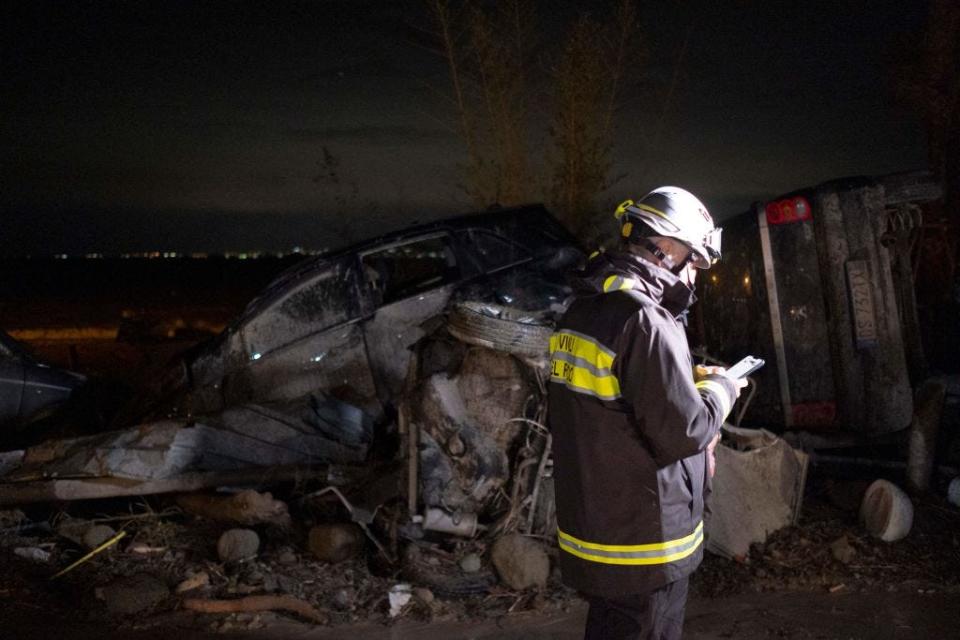 A firefighter stands next to damaged cars following heavy rains that caused a landslide on Ischia island on November 26, 2022.